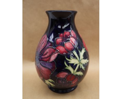 A Moorcroft pottery vase decorated in the Clematis pattern to a royal blue ground, impressed and painted marks, 19cm high 