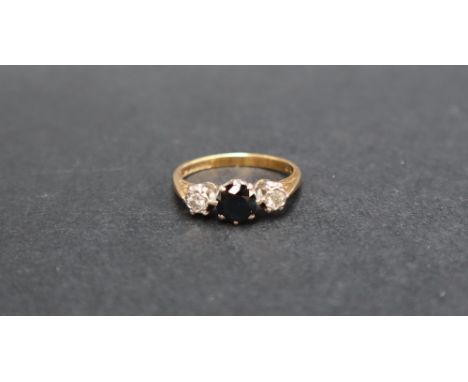 An 18ct yellow gold sapphire and diamond ring, set with a central round faceted sapphire flanked by two diamonds to a white m