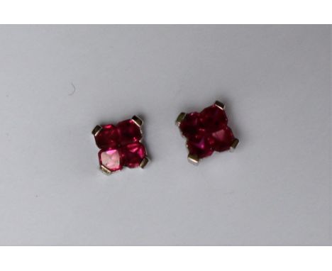 A pair of ruby earrings, each set with four princess cut rubies to a white metal setting and post, approximately 1.5 grams