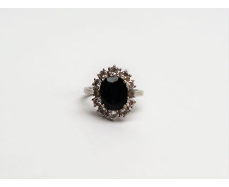 A diamond cluster ring, the central oval faceted stone possible a colour change sapphire, surrounded by round brilliant cut d