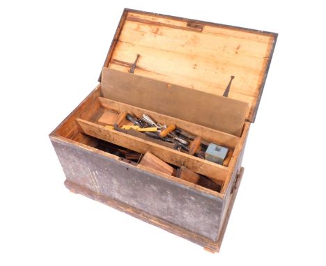 A stained pine carpenter's tool chest, containing moulding planes, braces, saws and other tools, chest 46cm high, 87cm wide, 