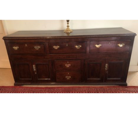 A George III oak dresser base, with moulded top, three drawers over two central drawers, flanked by two panelled doors, all w