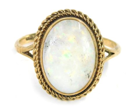 A 9ct gold opal dress ring, the oval opal in a rub over setting, with two row twist border, on V splayed shoulders, ring size