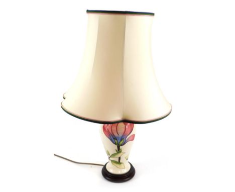 A Moorcroft pottery table lamp, decorated in the Magnolia pattern, against a cream ground, with matching shade, 65cm high. 