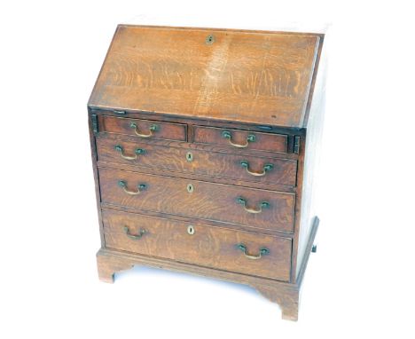 A George II oak bureau, with fall flap resting on lopers, revealing a fitted interior of drawers and pigeon holes, over two s