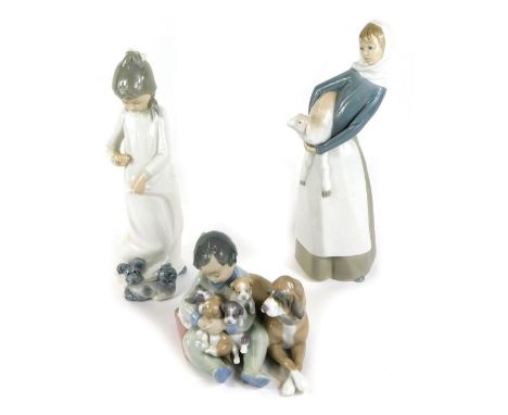 A Lladro porcelain figure group of a seated boy holding a clutch of puppies, a dog by his side, a further Lladro figure of a 