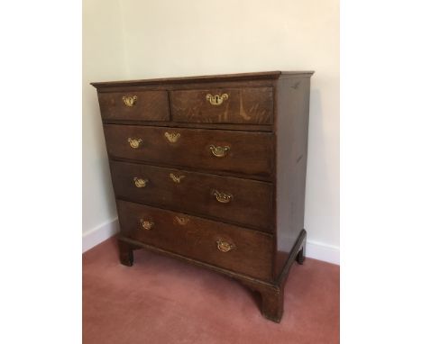 A George III oak chest, of two short and three long graduated drawers, with brass solid back plate handles, and bracket feet,