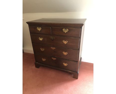 A George III oak chest, of two short and three long graduated drawers, with brass solid back plate handles and escutcheons, o