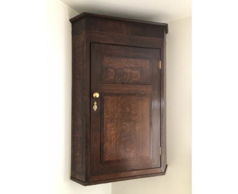 A George III oak hanging corner cupboard, with moulded top, and mahogany cross banding, oval shelf tier to the single door, 1