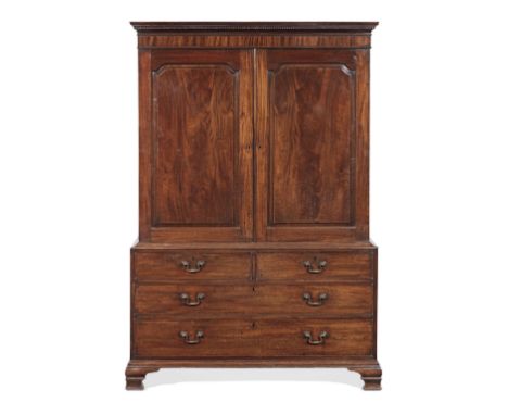 A late George II mahogany clothes press1755-60, the dentilled cornice above a pair of raised panelled doors with arched shape