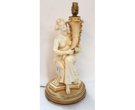 A cream pottery table lamp depicting a maiden holding a cornucopia marked AM Carrier Condition Report: Heavily stained and br