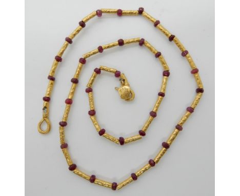 A bright yellow metal bead, and ruby bead necklace stamped 985k, length 40cm, weight 10.7gms Condition Report: Available upon