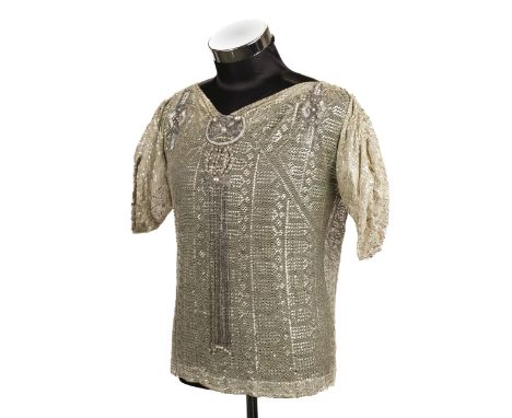 * Clothing. An Egyptian-style Assuit blouse, circa 1920s, cream net woven with hammered white metal pieces forming geometric 