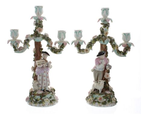 Pair of late 19th century German porcelain three-branch candelabra,&nbsp;the candle arms encrusted with flowers, raised on tr