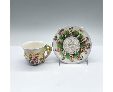 A set vintage espresso cup and saucer. Features raised reliefs of classical figures. Gilded floral on the center of the sauce