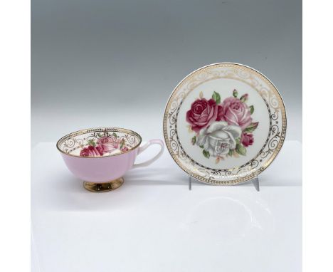 Pink and white tea cup and saucer set. The cup exterior is solid pink with a gilded base, and the interior features three pin