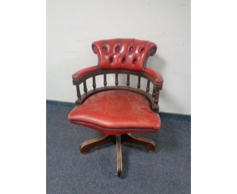 A captain's desk chair upholstered in a red button leather. 