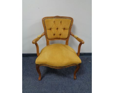 A carved beech framed armchair upholstered in a gold button dralon.  