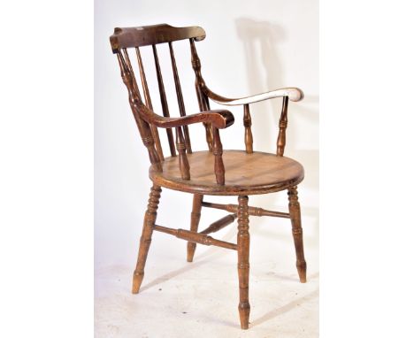 A 19th century Victorian Windsor smokers bow beech and elm armchair having bowed top rail over turned spindle back on carved 