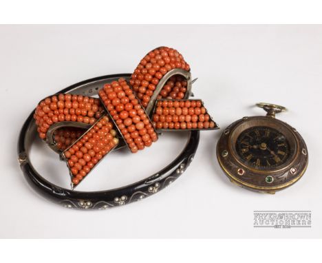 An antique coral brooch, c1870, in the form of a tied bow, mounted in silver; a silver and black enamel bracelet with split p