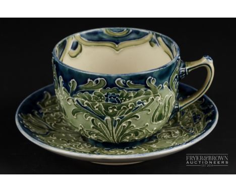 A Moorcroft MacIntyre pottery cabinet cup & saucer, Florian ware design of stylised flowering plants, blue/green colouration,