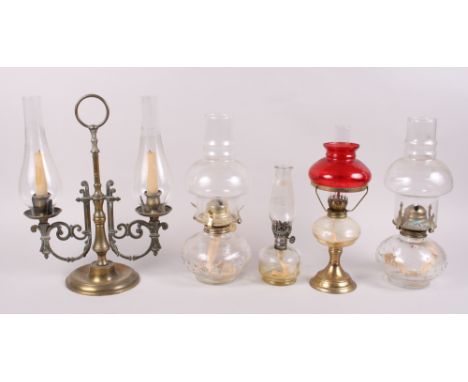 A brass two-light candelabra with glass shades and four oil lamps