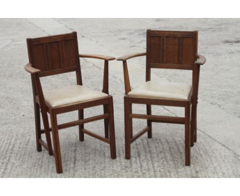 A pair of Ercol oak panel back elbow chairs with drop-in faux leather seats, on moulded and stretchered supports