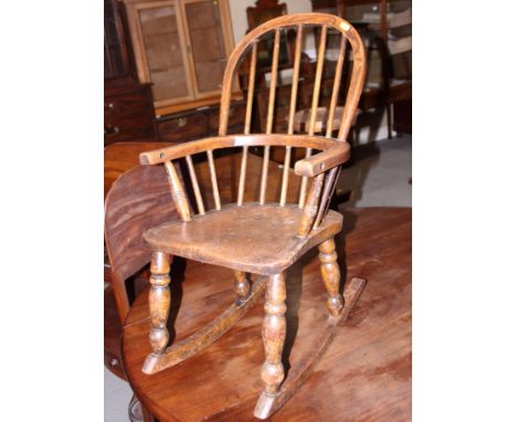 A child's Windsor stick back rocking elbow chair with elm panel seat