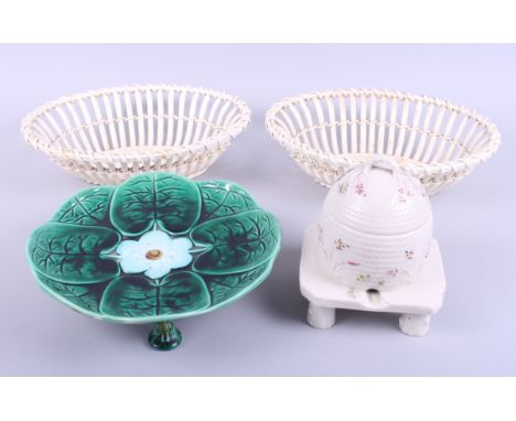 A Majolica plate, on three supports, a Belleek honey jar, on stand, and two china basketsCondition:Majolica plate is crazed.H