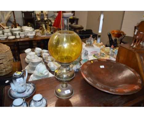 A brass oil lamp with yellow glass shade