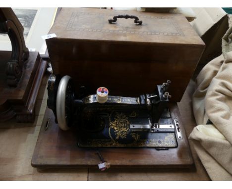 A wooden cased Singer sewing machine Together with a red painted trunk. 