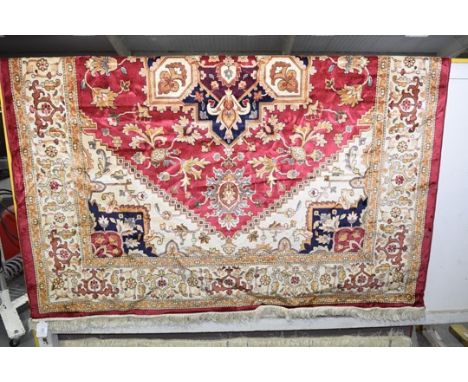 A Heriz style carpet with tasseled borders upon a red ground. (280 x 200cm) 