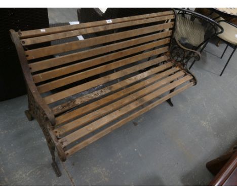 A Slatted garden bench on iron open work supports. 