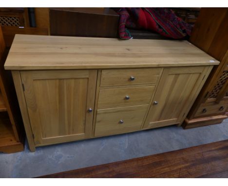 A Contemporary light oak sideboard with 3 central drawers flanked by cupboard doors. 