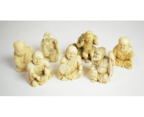 A small Japanese ivory Okimono, Meiji period, carved as a man seated beside a basket with gourd across shoulders, 4.5cm width