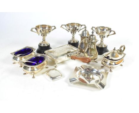 A small group of silver comprising a five piece condiment set; three small trophy cups; a vesta case; an ashtray with enamel 