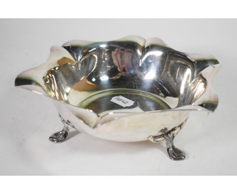 An Art Nouveau silver dish, H Pidduck &amp; Sons, Sheffield 1916, shaped rim, on three stylised  hoof supports, 24cm diameter