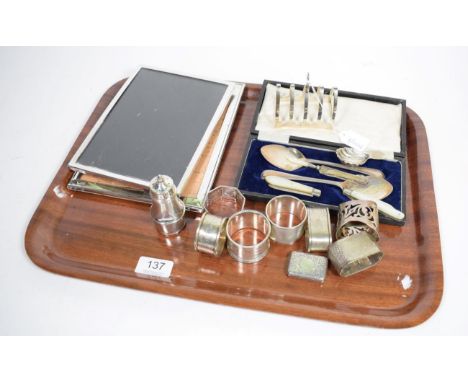 A group of assorted silver items to include: two photograph frames; various napkin rings; a toast rack; fruit knives; caddy s