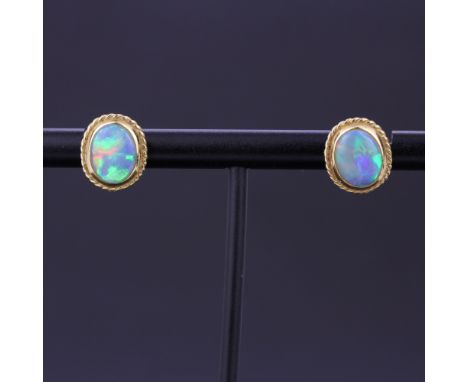 A pair of yellow metal opal set stud earrings, L. 1cm. With 18ct gold backs.