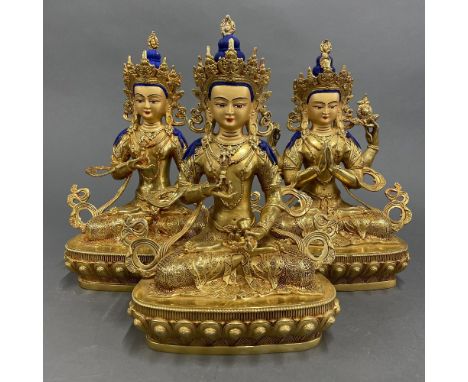 A group of three Tibetan gilt bronze figures of seated Bodhisatva with temple quality faces. H. 29cm.