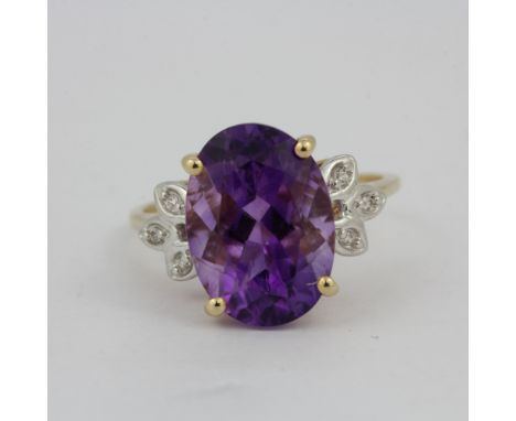 A 10ct yellow gold (stamped 10K) ring set with a large oval cut amethyst, L. 1.5cm, and diamond shoulders, (O.5).