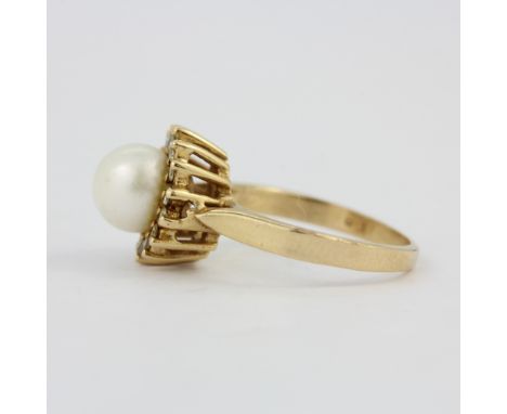 A 14ct yellow gold (stamped 14K) ring set with a cultured pearl surrounded by diamonds, (G).