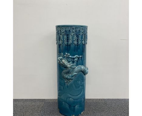 A large Chinese glazed ceramic umbrella stand, relief decorated with a dragon. Some chipping present, H. 60cm.