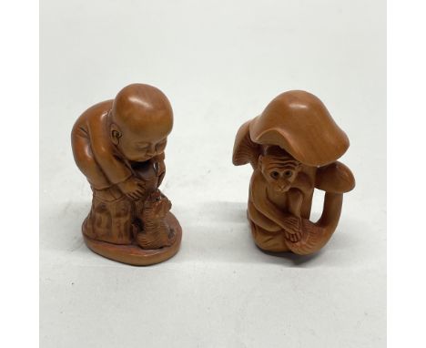 A small Chinese carved fruitwood netsuke of a monkey and mushrooms, together with a netsuke of a monk playing with a puppy, w