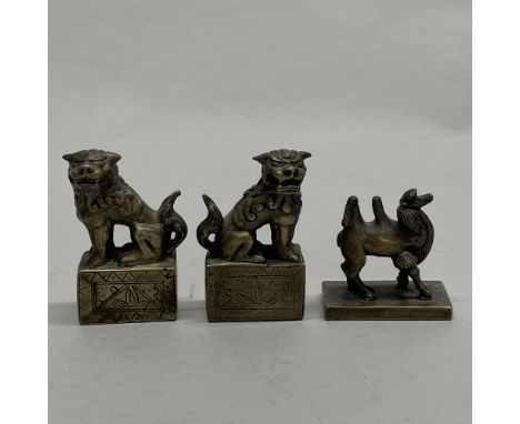 A pair of Chinese cast bronze seals decorated with liondogs, together with a further cast bronze seal in the shape of a camel