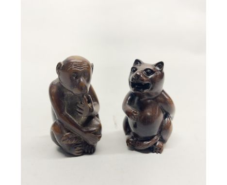 A Chinese carved wooden netsuke of a monkey, together with a further carved wooden netsuke of a cat, H. 5cm.