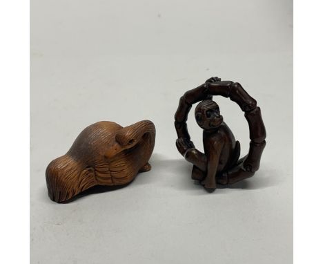 A Chinese craved wooden netsuke of a resting crane, together with a further carved wooden netsuke of a monkey in bamboo, sign