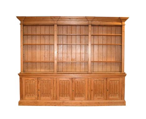 Large pitch pine bookcase, inverted breakfront moulded cornice, open adjustable shelves, the base with linenfold doors, plint