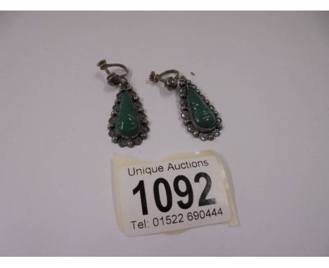 A pair of vintage silver pendant earrings featuring Mexican faces (possibly jade).