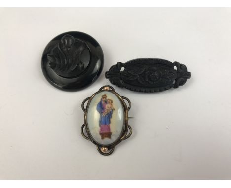 Victorian and later brooches, including a jet boss-form brooch, the centre carved with a fruiting vine, one further faux-jet 